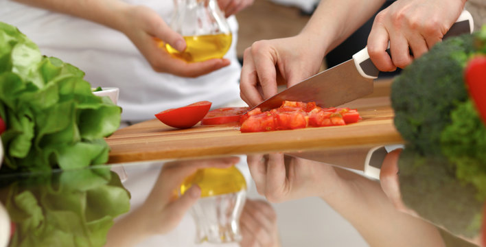 Closeup Of Human Hands Cooking In Kitchen. Mother And Daughter Or Two Female Friends Cutting Vegetables For Fresh Salad. Friendship, Family Dinner And Lifestyle Concepts