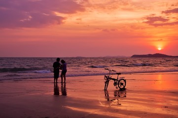 Silhouette of couple standing on the beach with dramatic sunset sky