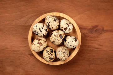 A photo of quail eggs, shot from the top on a dark rustic wooden background with a place for text