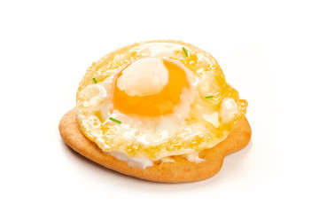 A photo of a quail egg, fried sunny side up, on a cracker on a white background with a place for text