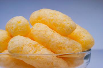 Zoomed Corn Puffs in a Glass Bowl. Crunchy Flavored Puffed Snacks. Party, Movie Snacks.