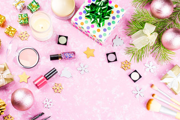 Make up cosmetics, presents and Christmas decorations on artistic pink background, copy space