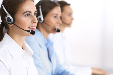 Call center. Group of operators at work. Focus at beautiful business woman in headset