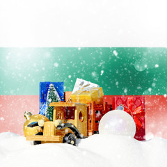 Christmas background.Toy truck with gifts, New Year fir, balls in the snowdrift and Bulgarian flag