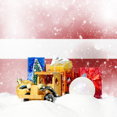 Christmas background.Toy truck with gifts, New Year fir, balls in the snowdrift and Latvian flag