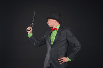 Retro style detective agent with gun and bowler hat on his head isolated on the black background.