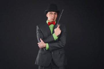 Retro style detective agent with gun and bowler hat on his head isolated on the black background.