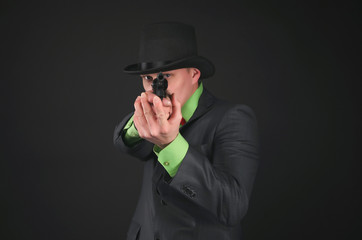 Retro style detective agent with gun and bowler hat on his head is aiming forwards isolated on the...