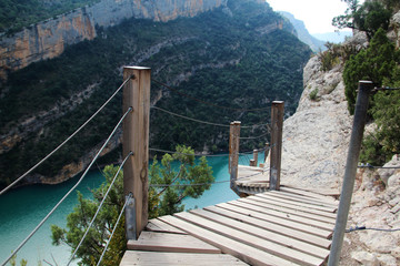 Obraz premium A wooden staircase at rock cliff as part of hiking path in Mont Rebei canyon, Spain 