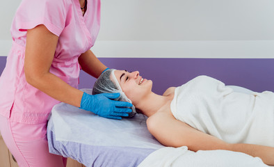 Facial cosmetic procedure in spa salon. The procedure for applying a mask to the face of a beautiful woman