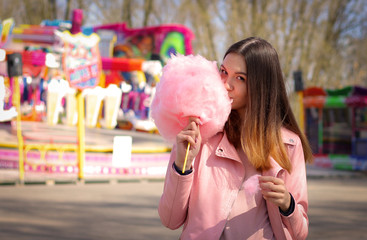 Obraz premium Young woman standing with pink cotton candy p in amusement Park