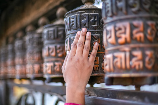 Woman hand touching and spinning prayer wheels of Swayambhunath Stupa in Kathmandu, Nepal
