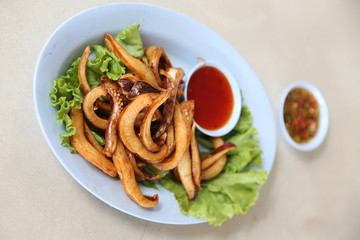 Thai Fried Squid with Chilli Sauce In a blue plate on a white table, Selective focus.