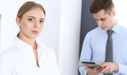 Fototapeta premium Beautiful blonde businesswoman using tablet pc while standing straight in a brightly lit office. Business concept