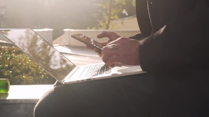 Close up businessman working  in the park on his laptop and cellphone