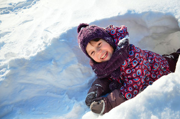 Fototapeta na wymiar Little cute laughing kid having fun in snow. Happy childhood concept. Sunny winter day