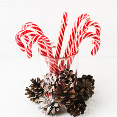 Many red christmas candy canes in glass with pine cones decoration