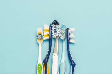 Several different used toothbrushes on a blue background. Toothbrush change concept, oral hygiene,...