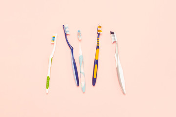 Obraz na płótnie Canvas Several different used toothbrushes on a pink background. Toothbrush change concept, oral hygiene, big and friendly family, toothbrush selection. Flat lay, top view
