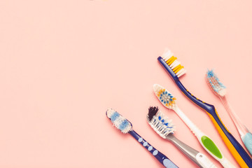 Several different used toothbrushes on a pink background. Toothbrush change concept, oral hygiene, big and friendly family, toothbrush selection. Flat lay, top view