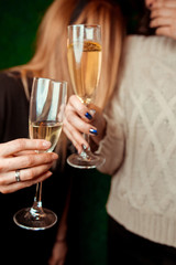 two girls clink glasses of champagne on a beautiful summer terrace. sparkling champagne glasses. close up