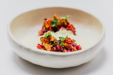 Meat tartare with mushrooms, sauce and greenery on a white plate