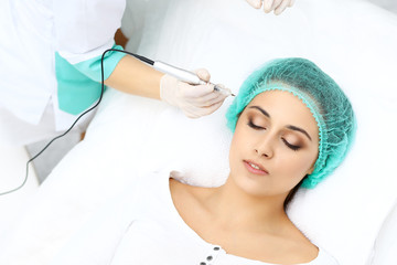 Obraz na płótnie Canvas Professional beautician doing eyebrow tattoo at woman face. Permanent brow makeup in beauty salon, closeup. Cosmetology treatment