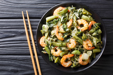 Delicious peeled king prawns with a refreshing mix of pak choi, spinach, soy beans and sugar snap peas closeup. horizontal top view