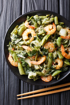 Chinese traditional Stir frying of shrimp, spinach, soy sprouts, pea pods and pak choi close-up on a plate. Vertical top view