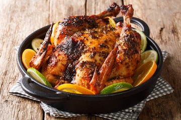 Traditional Cuban mojo chicken dish baked and served with fresh oranges and limes closeup in a pan. horizontal