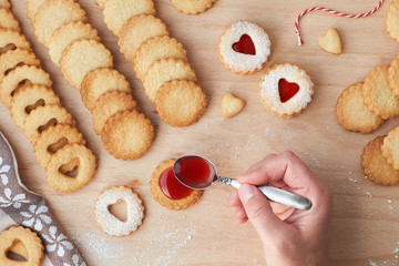 Top view of traditional Christmas Linzer cookies filled with strawberry jam on wooden board.
