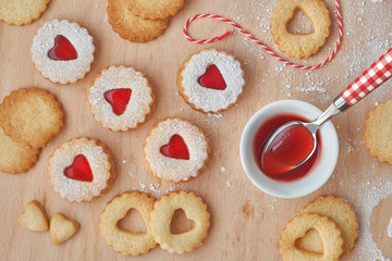 Top view of traditional Christmas Linzer cookies filled with strawberry jam on wooden board.