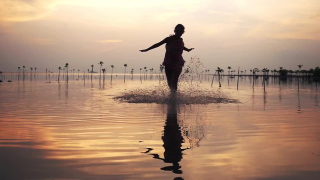 Pretty, young woman in short dress and sunglasses running on the beach during beautiful sunset. 1920x1080