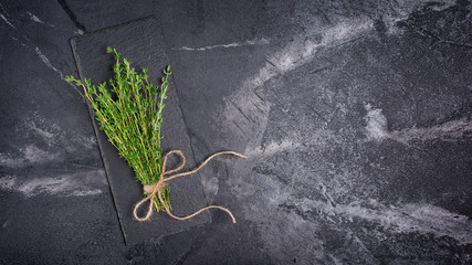 Top view on fresh thyme green herb with twine rope on black slate board