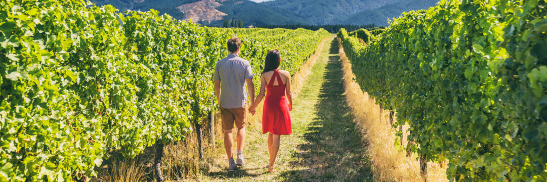 Winery vineyard tourists couple walking on wine farm tour on travel vacation. Wine tasting holiday panoramic banner.