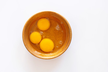Egg yolks in wooden bowl on white