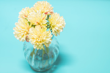 White flowers are arranged in a vase, placed on a blue table.