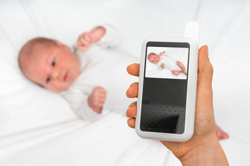 Mother is holding baby monitor camera for safety of her baby