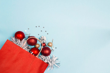 Red shopping bag with christmas decoration on a blue background and copy space.