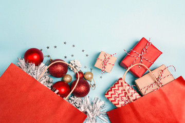 Red shopping bags with christmas decoration and gifts  on a blue background.