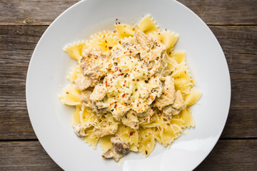 Fresh pasta with chicken, mushrooms and cheese on the rustic wooden background. Selective focus.