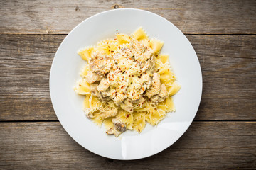 Fresh pasta with chicken, mushrooms and cheese on the rustic wooden background. Selective focus.