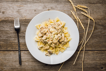 Fresh pasta with chicken, mushrooms and cheese on the rustic wooden background. Selective focus.