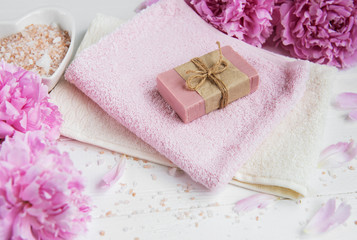 Fototapeta na wymiar bars of handmade soap, soft towels and peony flowers