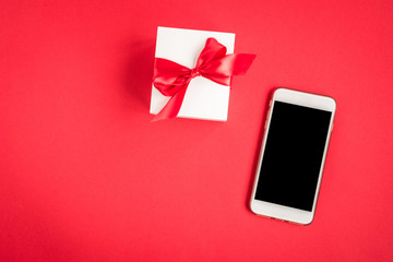 Mobile phone and gift box on red background.