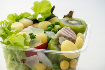 Salad of fresh vegetables and healthy grains ,In clear plastic box,On a white background