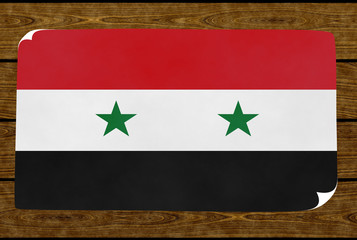 Illustration of a Syrian flag on the paper pasted on the woody wall