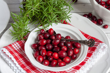 Red cranberries in a white porcelain bowl with a silver spoon