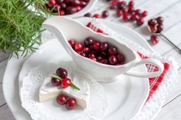 Camembert cheese and a porcelain sauceboat with cranberries and rosemary