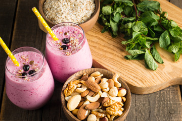 Glasses of berry smoothie with nuts, mint, blueberry, blackberry, raspberry, and yogurt on wooden table. Weight loss and diet concept. 